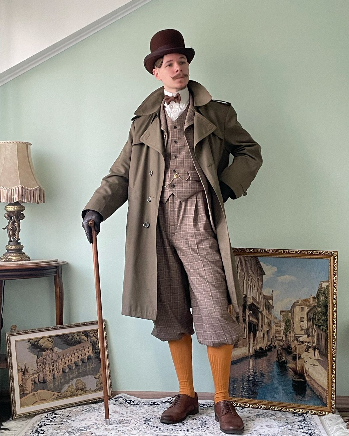 Man in 19th century attire with bowler hat, overcoat, and plaid knickerbockers.