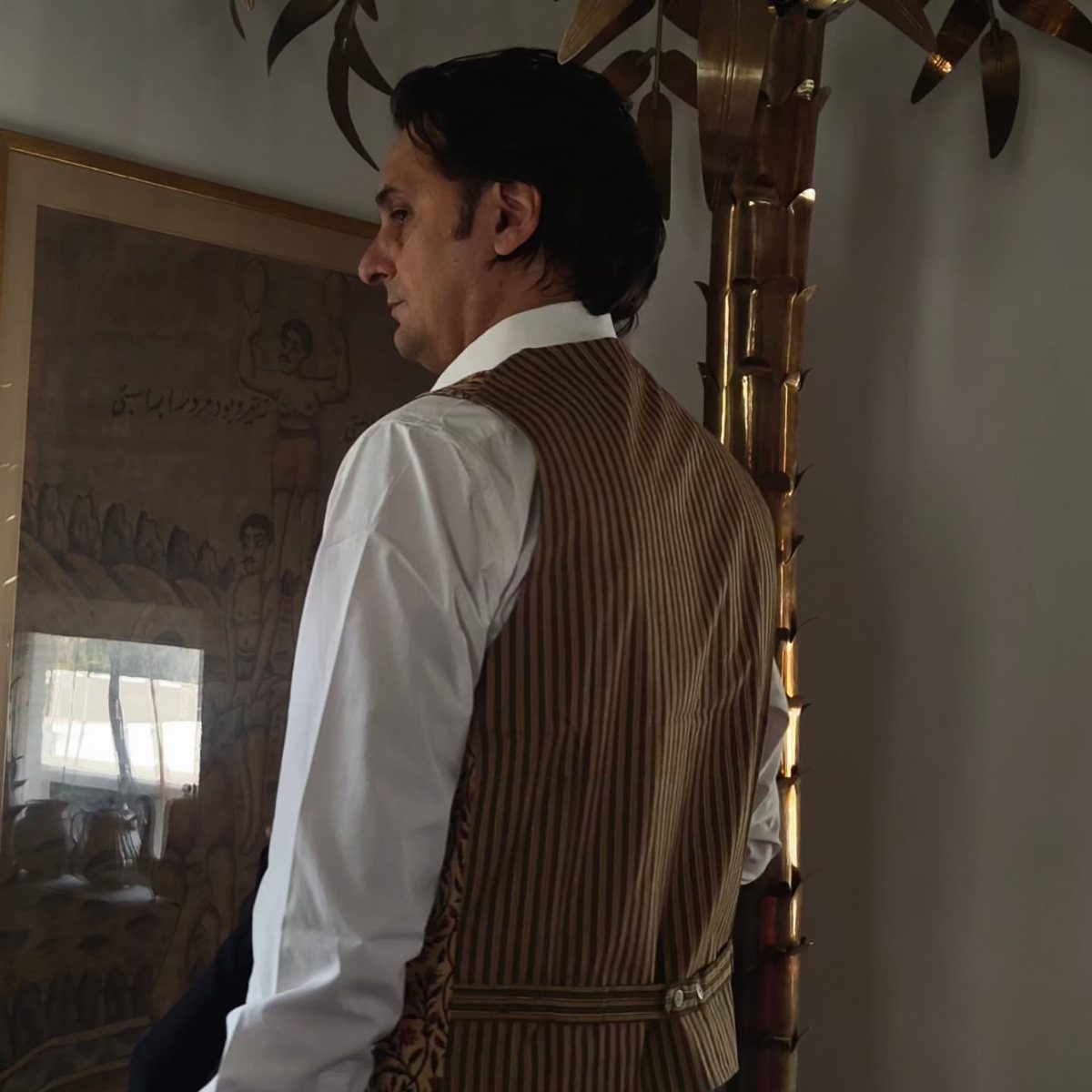 Man wearing a striped brown waistcoat and white shirt in a vintage style.