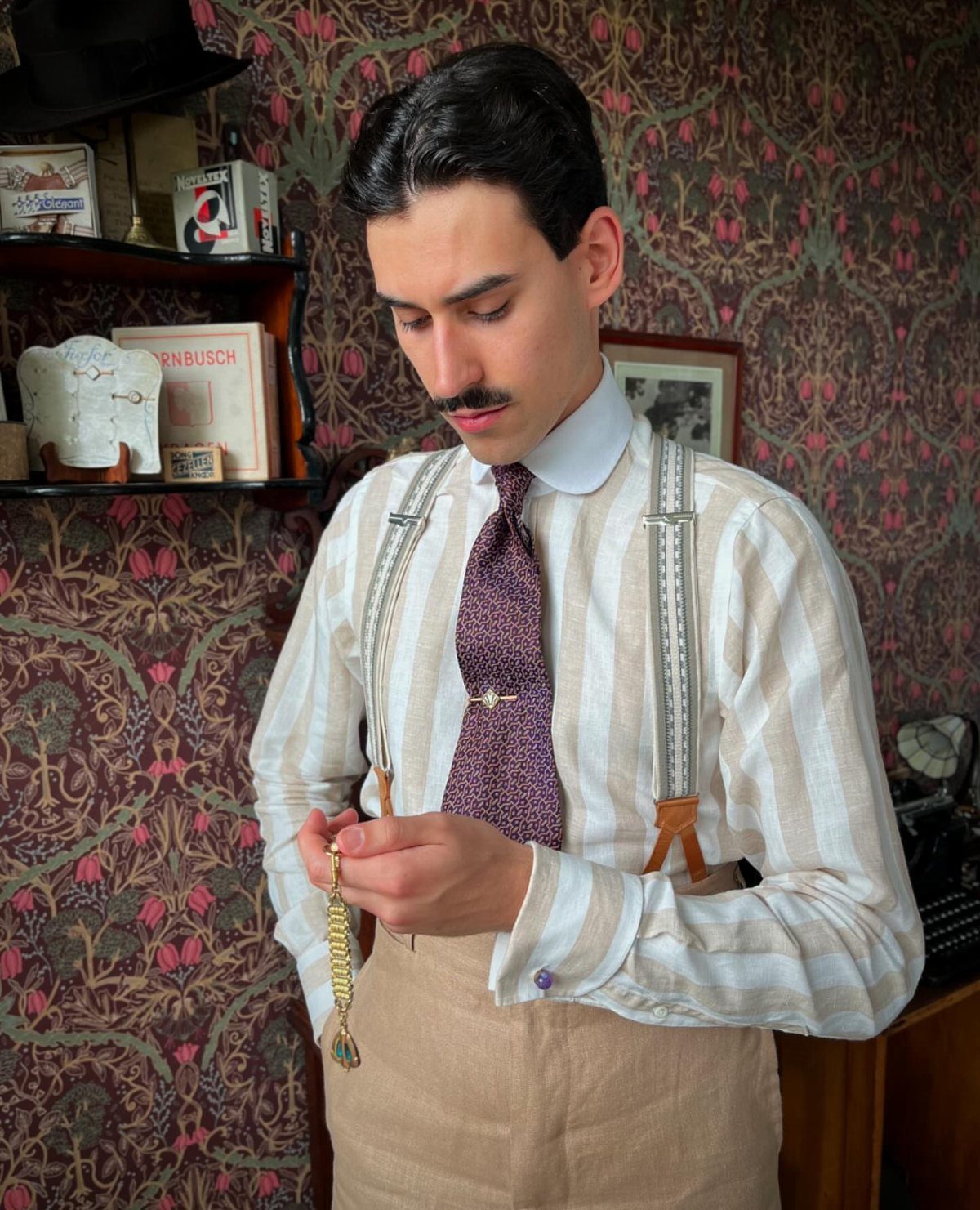Man in 1920s fashion wearing a striped shirt, suspenders, and purple tie.
