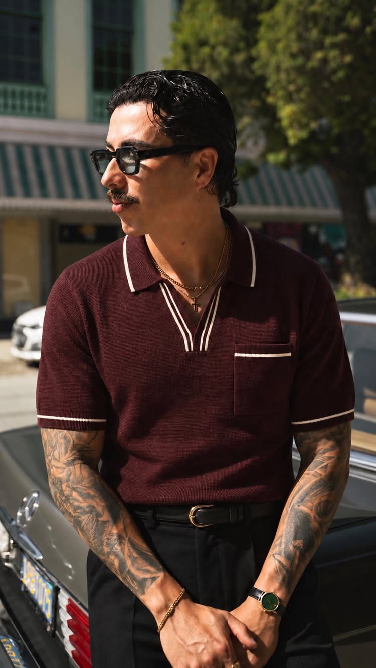 Man in maroon knit polo and sunglasses leaning against a vintage car.