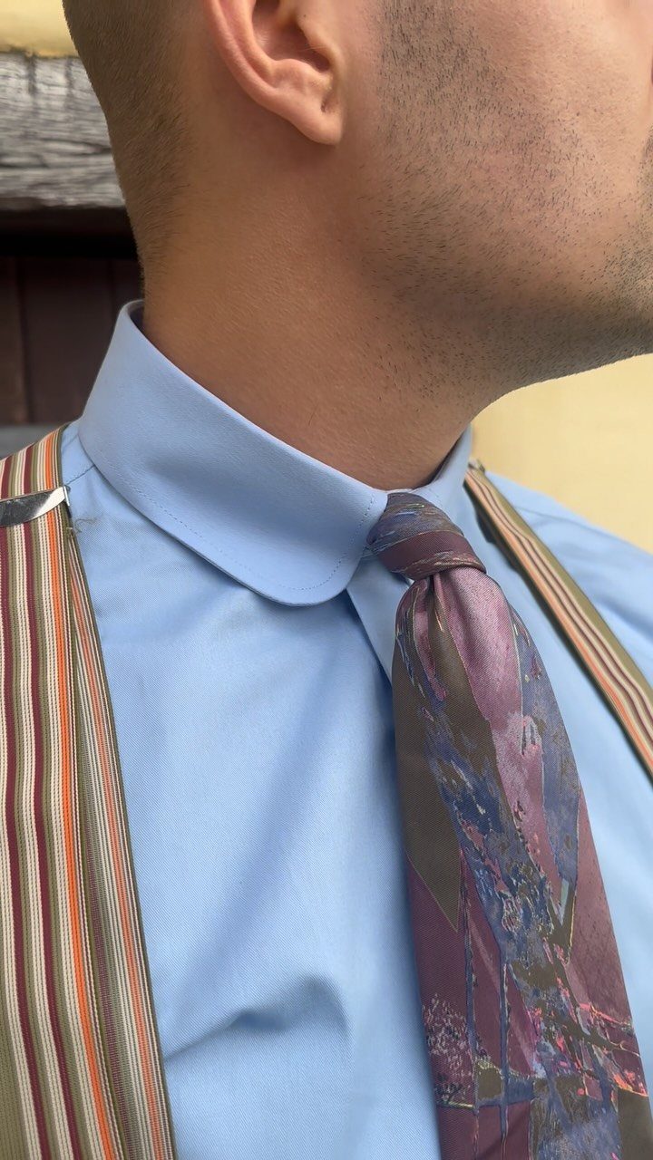 Man wearing a light blue shirt with a rounded club collar and patterned tie.