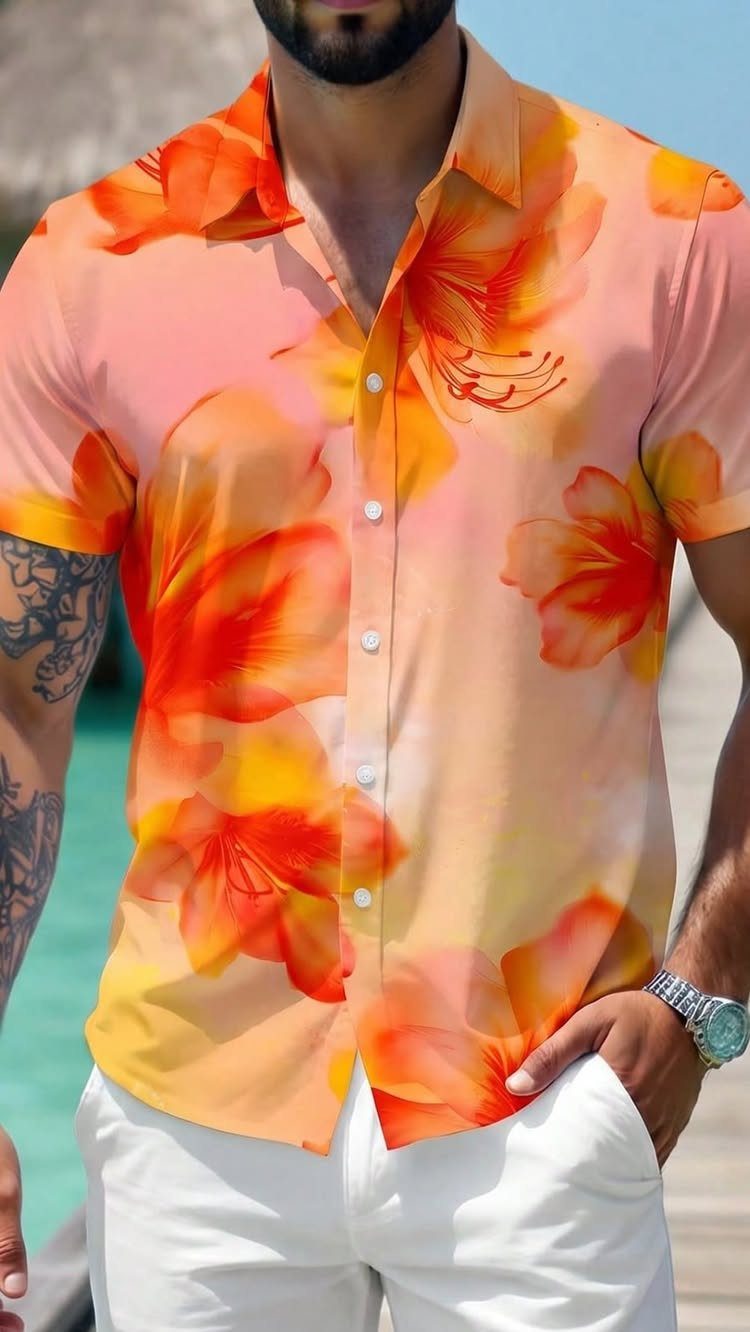 Man wearing an orange floral print shirt and white trousers standing outdoors.