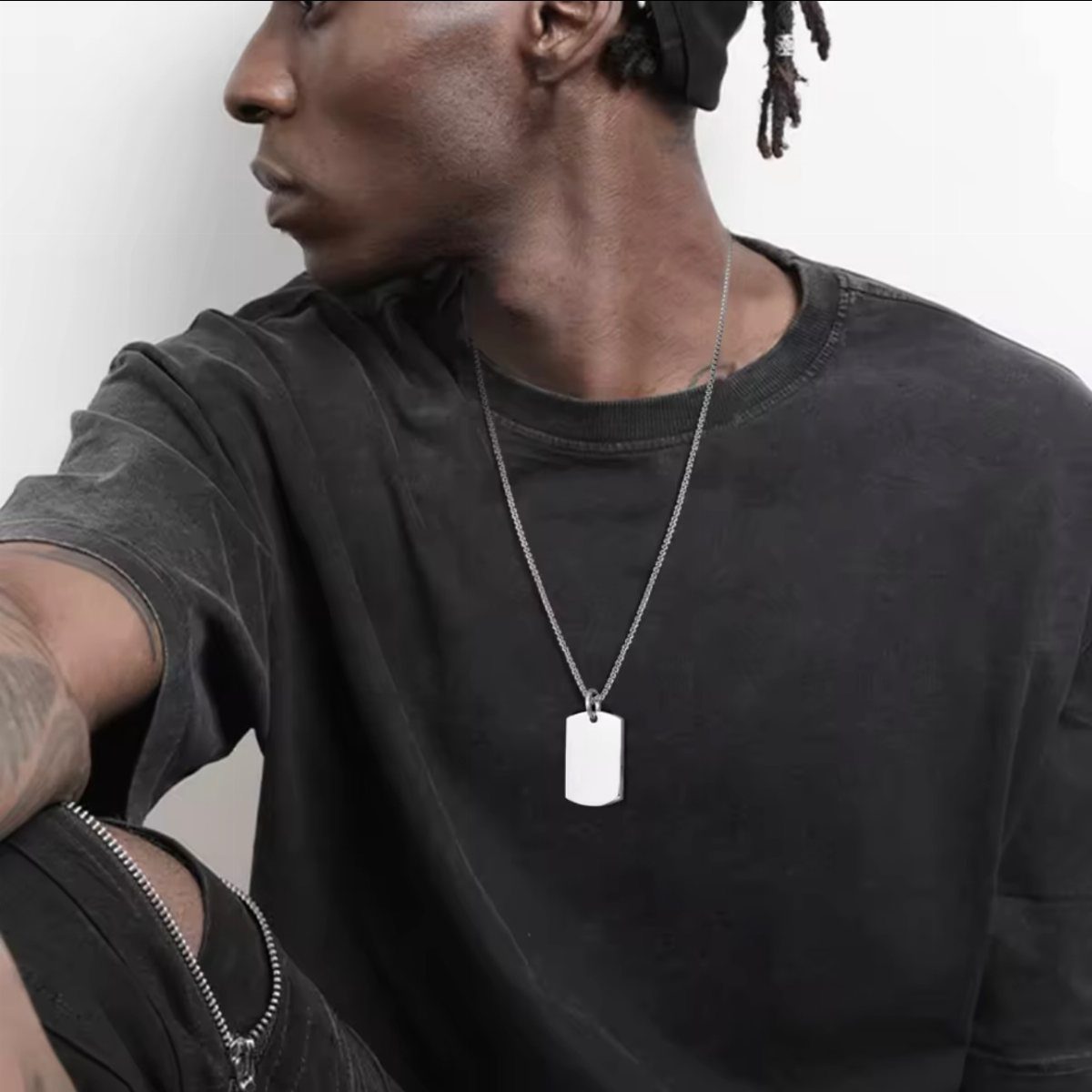 Man in dark grey t-shirt wearing a silver chain with a dog tag pendant