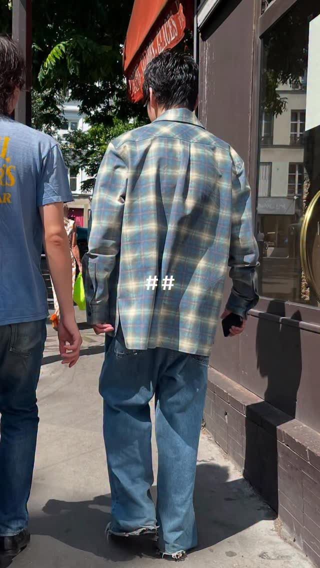 Man from behind wearing a blue plaid shirt and wide-leg blue jeans.