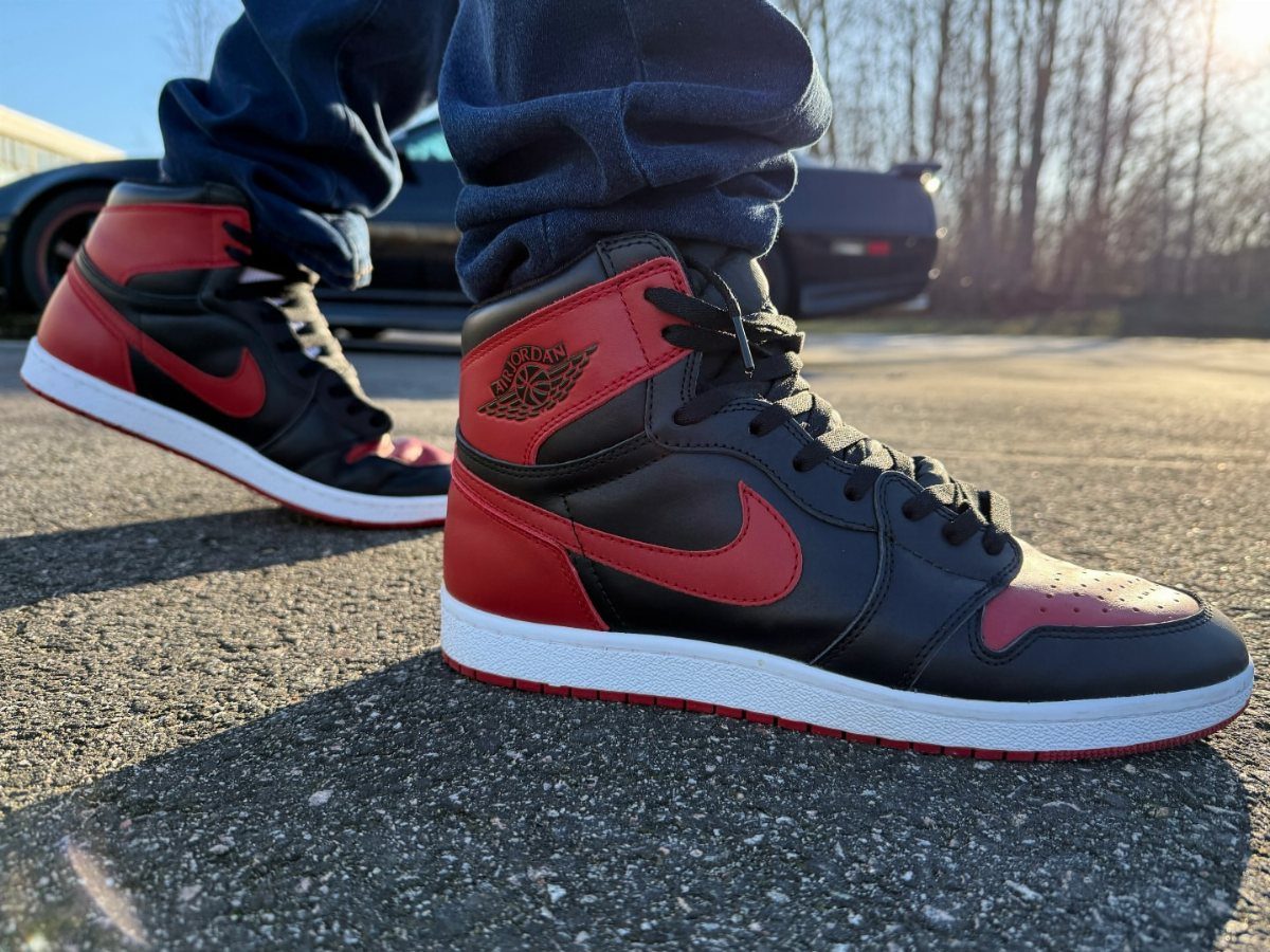 Black and red Nike Air Jordan 1 High sneakers worn with blue jeans.
