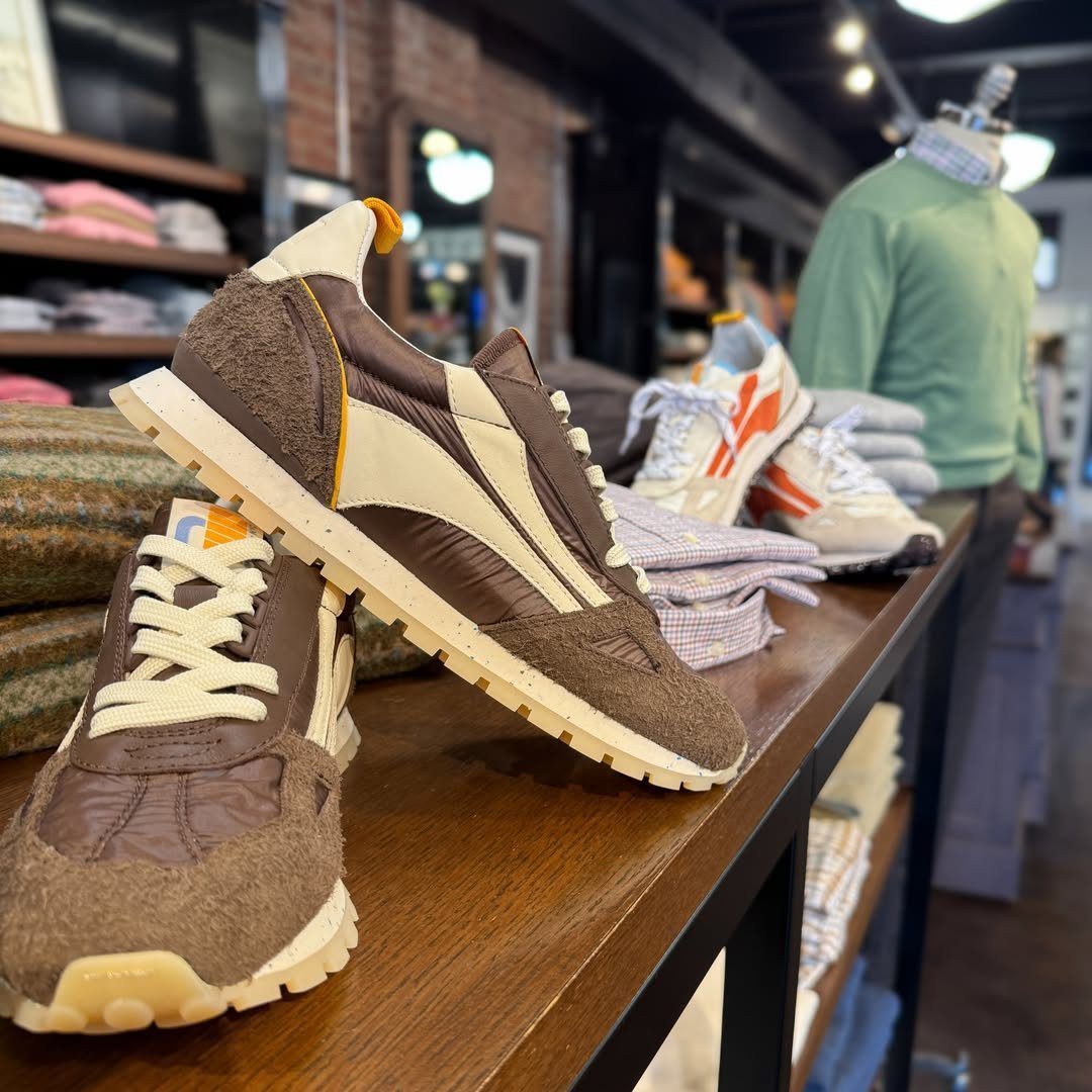 Brown and beige Puma sneakers displayed on a wooden shelf in a clothing store.