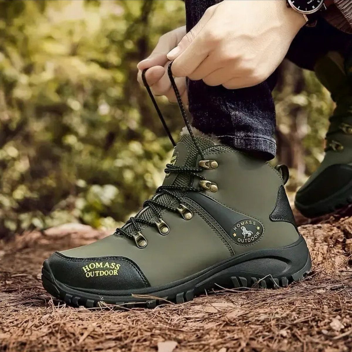 Olive green hiking boot being laced up on a forest floor.