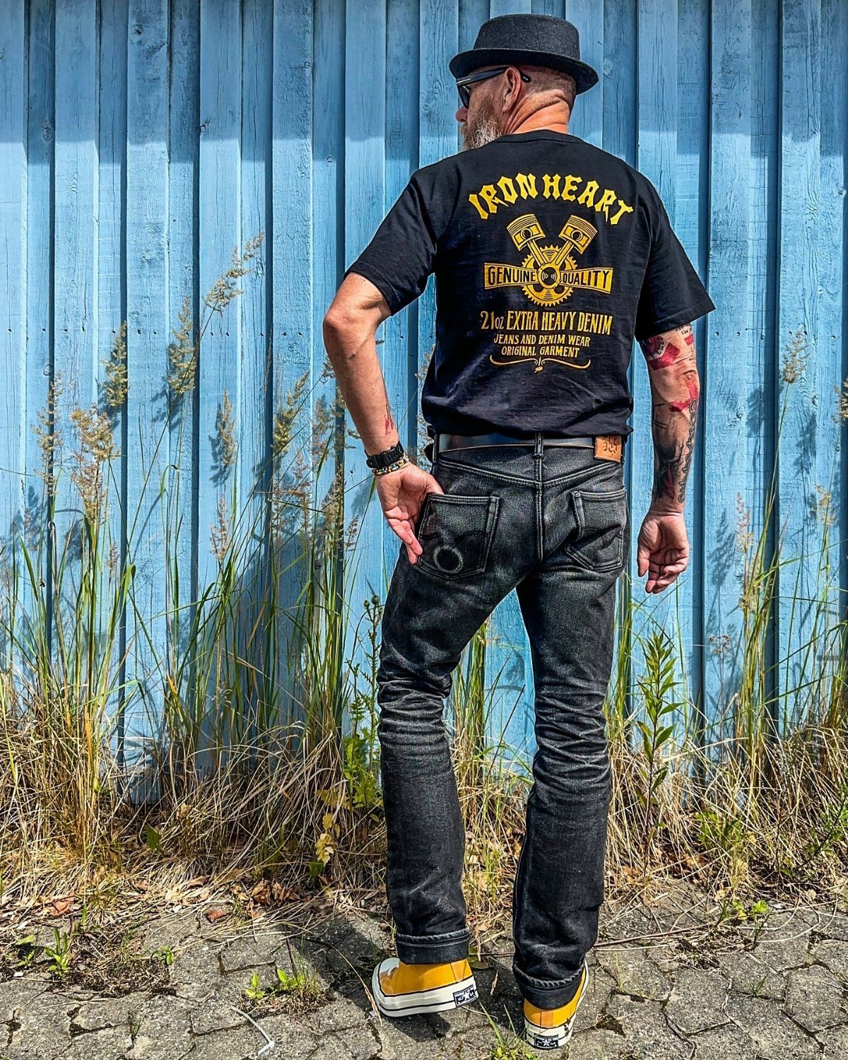 Man wearing a black pork pie hat, black t-shirt, and dark grey jeans.