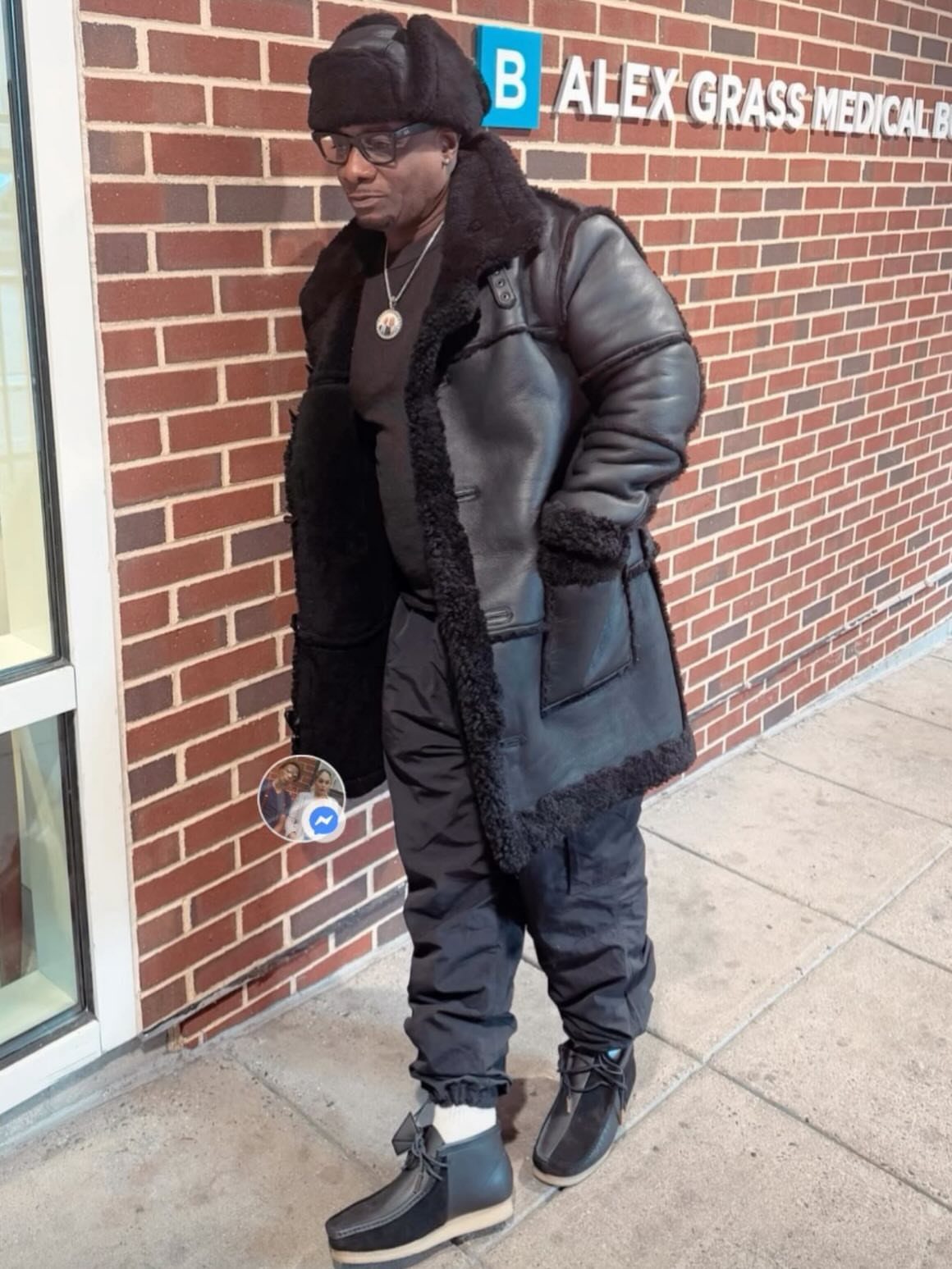 Man wearing a black trapper hat, shearling coat, and black snow pants.