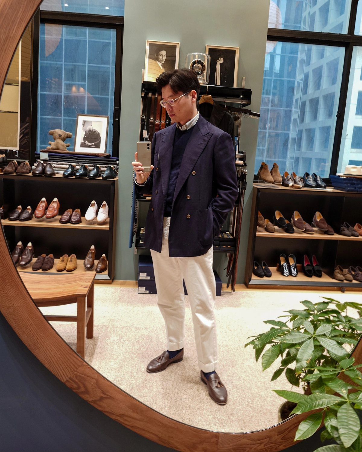 9 Men's Holiday Party Fashion Ideas That Actually Work 4 Man wearing a navy sport coat, white chinos, and brown loafers in a store.