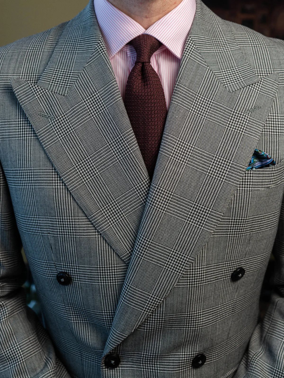 9 Men's Holiday Party Fashion Ideas That Actually Work 2 Man wearing a grey glen plaid double-breasted suit with a pink striped shirt.