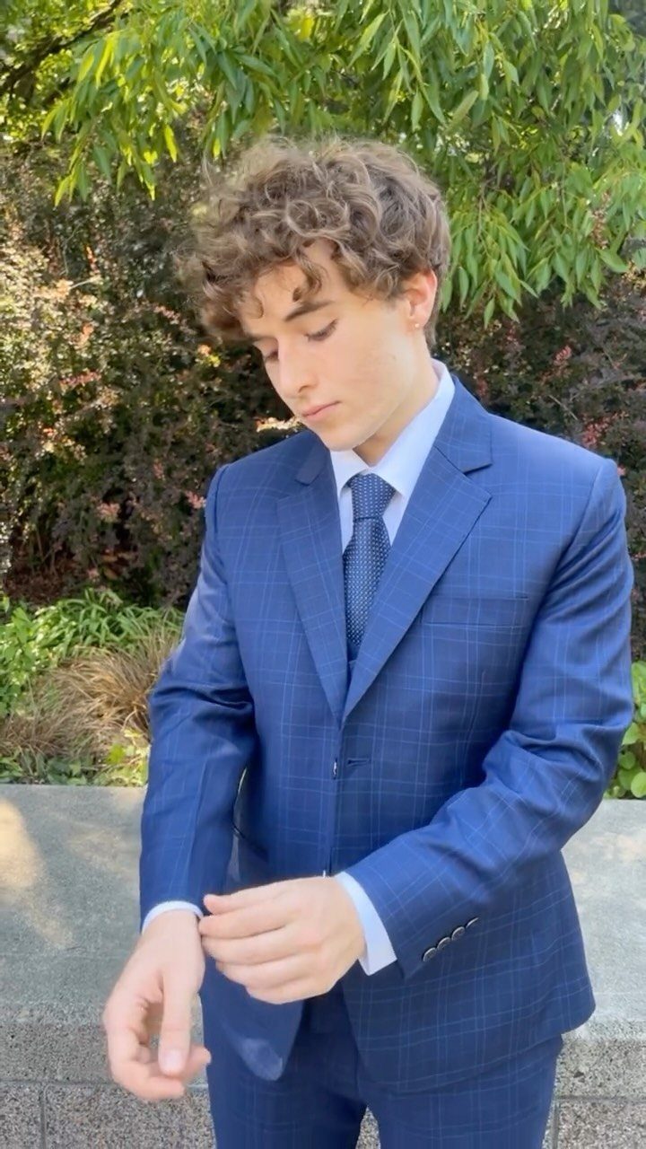 Young man wearing a blue plaid modern prom suit and tie outdoors.