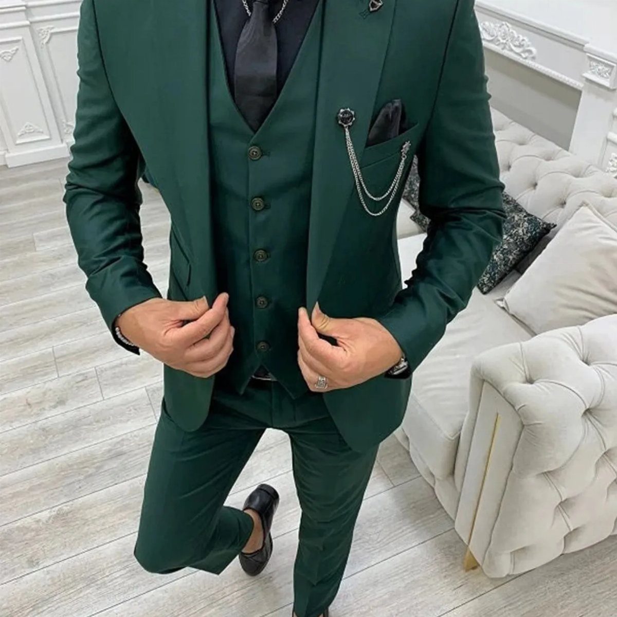 Man in a dark green three-piece suit with a black shirt and tie