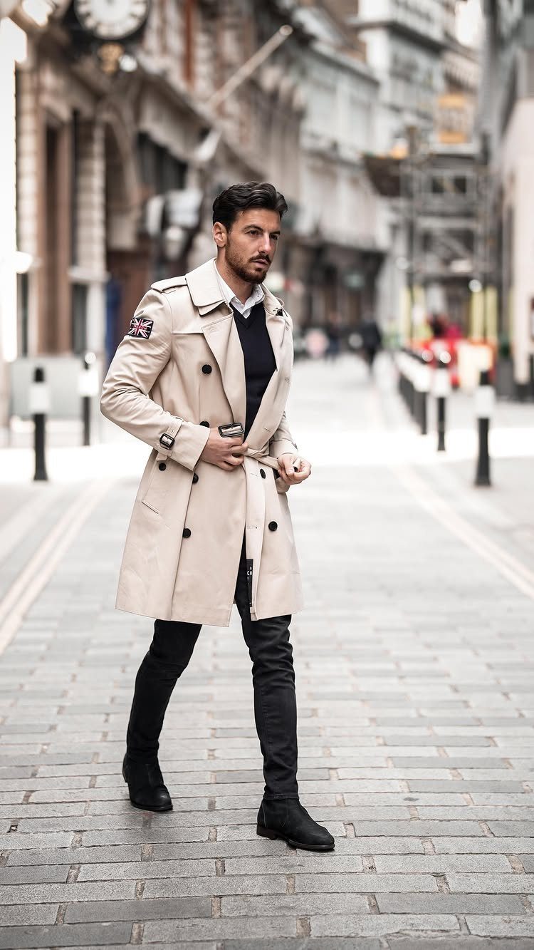 Man in a beige long trench coat and black skinny pants on city street