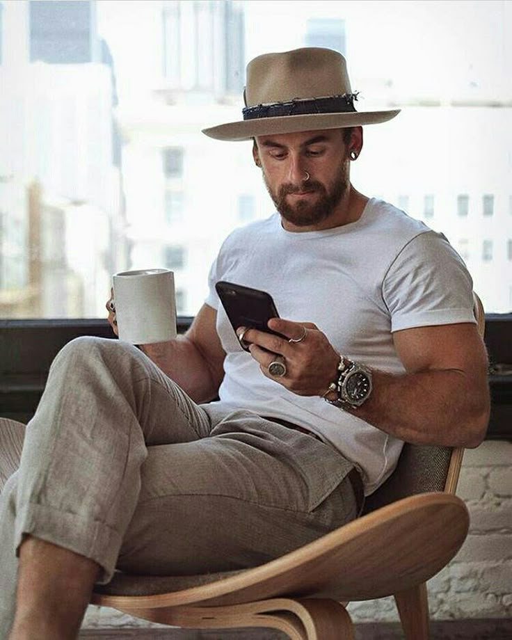 Man wearing a tan wide-brimmed summer hat, white t-shirt, and linen trousers.