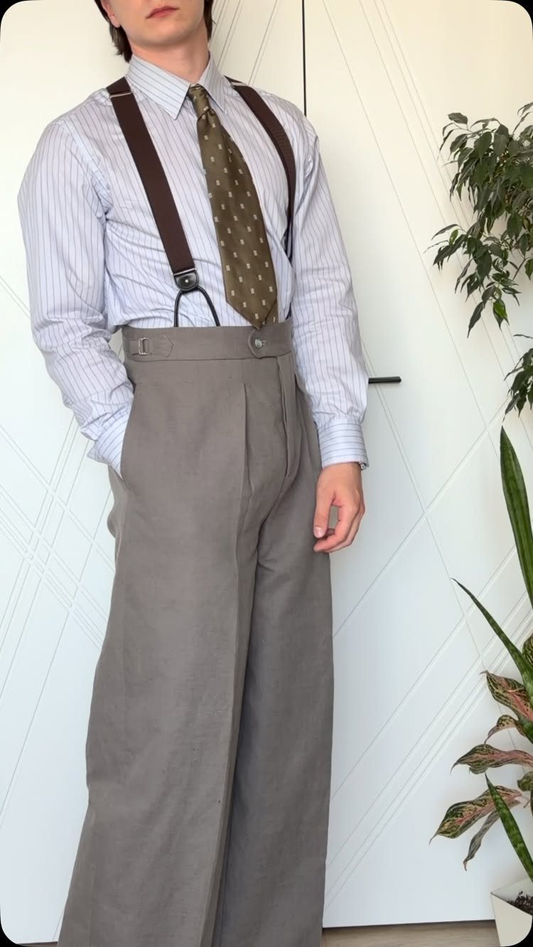 Man wearing high-waisted grey trousers, brown suspenders, and a striped shirt with tie.