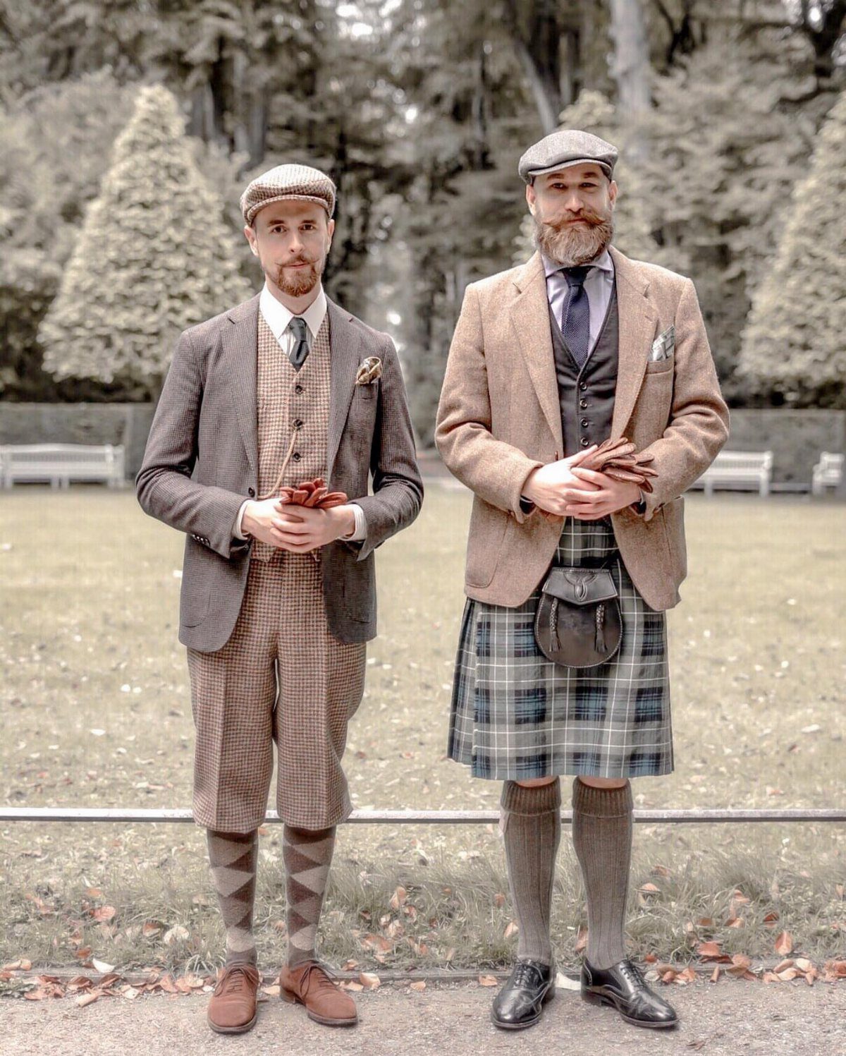 Two men wearing vintage tweed jackets, flat caps, and traditional knickerbockers and a kilt.