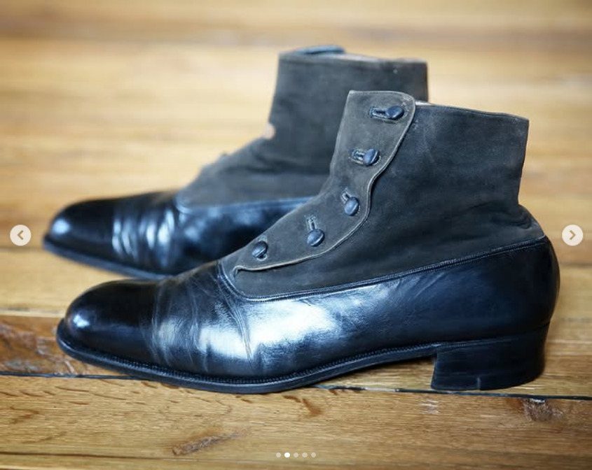 Black leather and suede Victorian boots with side buttons on a wooden floor