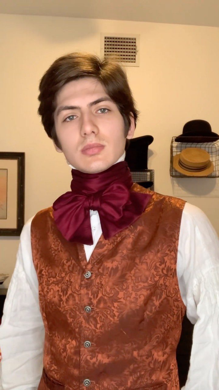 Man wearing a copper brocade vest and maroon cravat in Victorian style clothing.