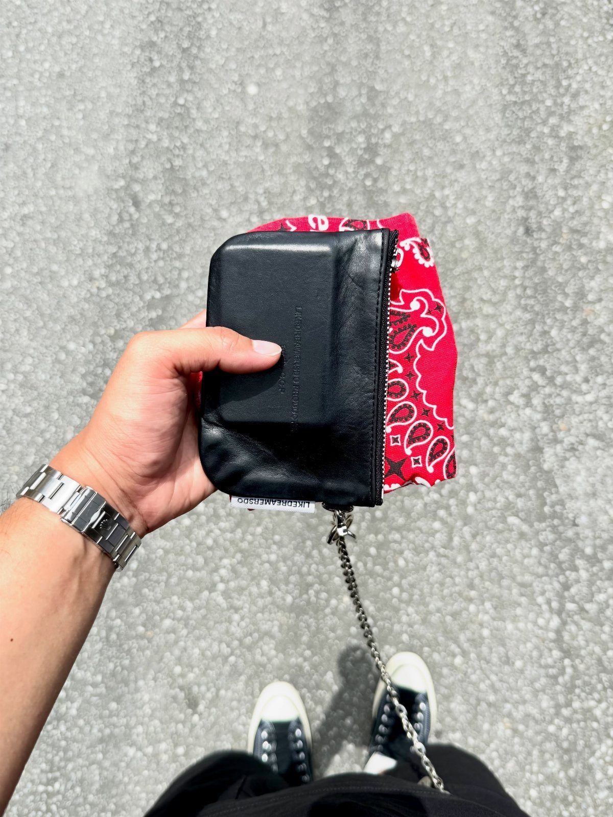 Black leather zip-around wallet with silver chain held against a red paisley bandana.