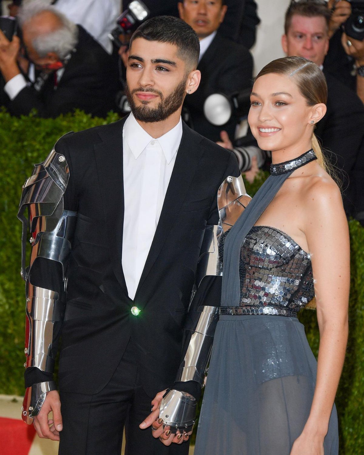 Zayn Malik in a black suit with robotic arm armor and Gigi Hadid in grey.
