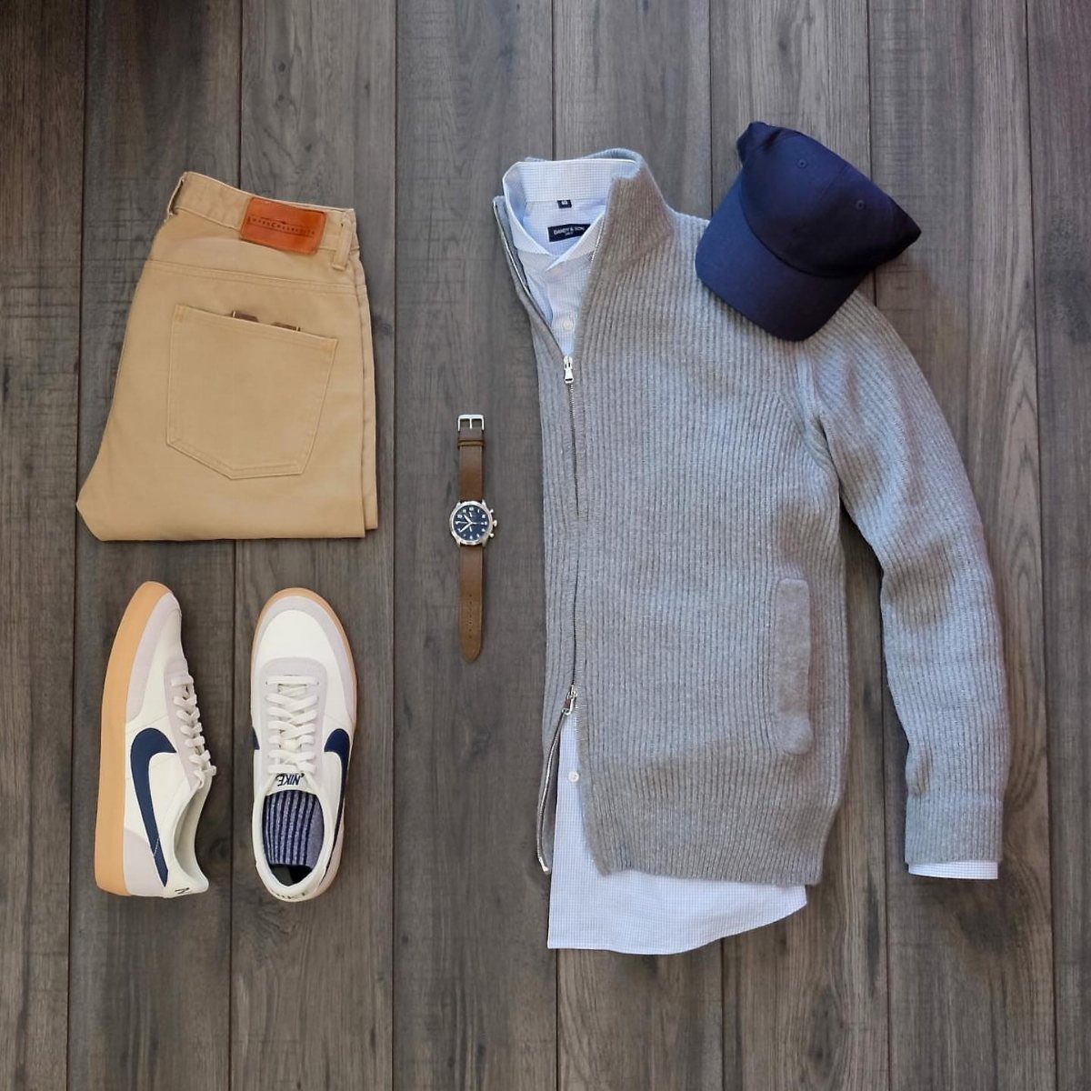Men's business casual outfit with blue shirt, grey cardigan, tan trousers, and white sneakers.
