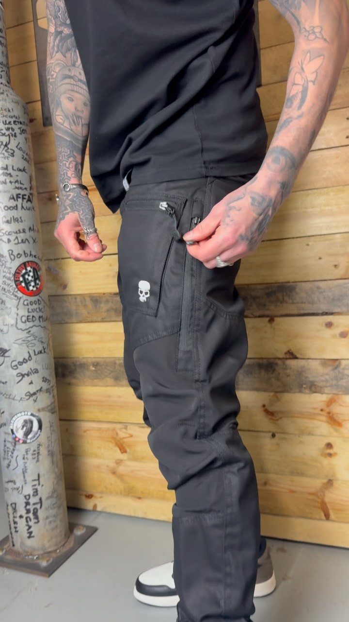 New Men's Fashion Pants: 12 Styles to Refresh Your Wardrobe 2 Man wearing black cargo pants with side pockets and a skull logo.