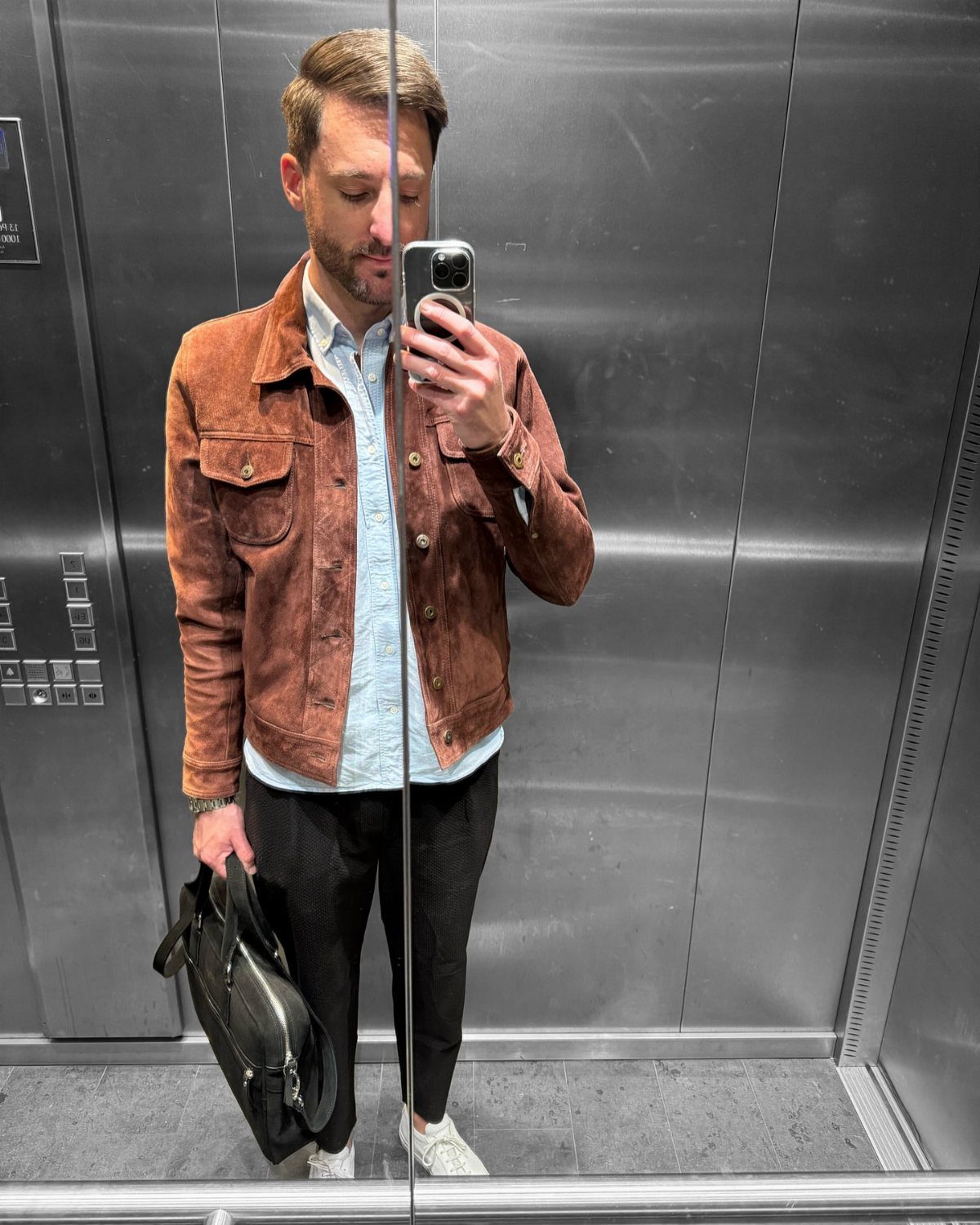New Men's Fashion Pants: 12 Styles to Refresh Your Wardrobe 12 Man in a brown suede jacket and black trousers taking a mirror selfie.