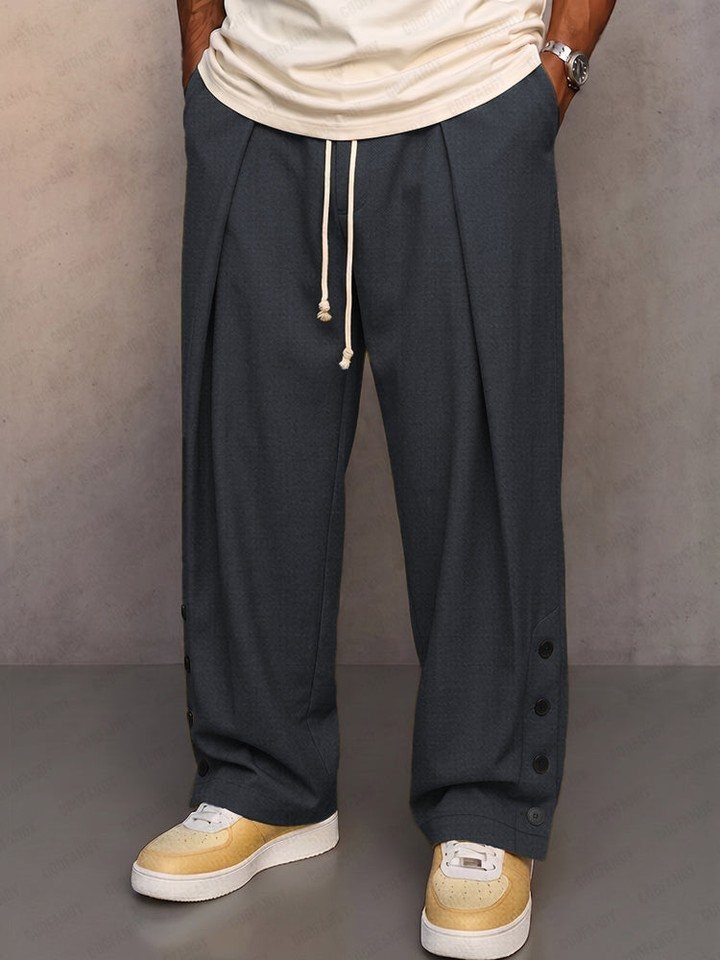 New Men's Fashion Pants: 12 Styles to Refresh Your Wardrobe 5 Dark grey wide-leg trousers with white drawstring waist and pleats and tan sneakers.