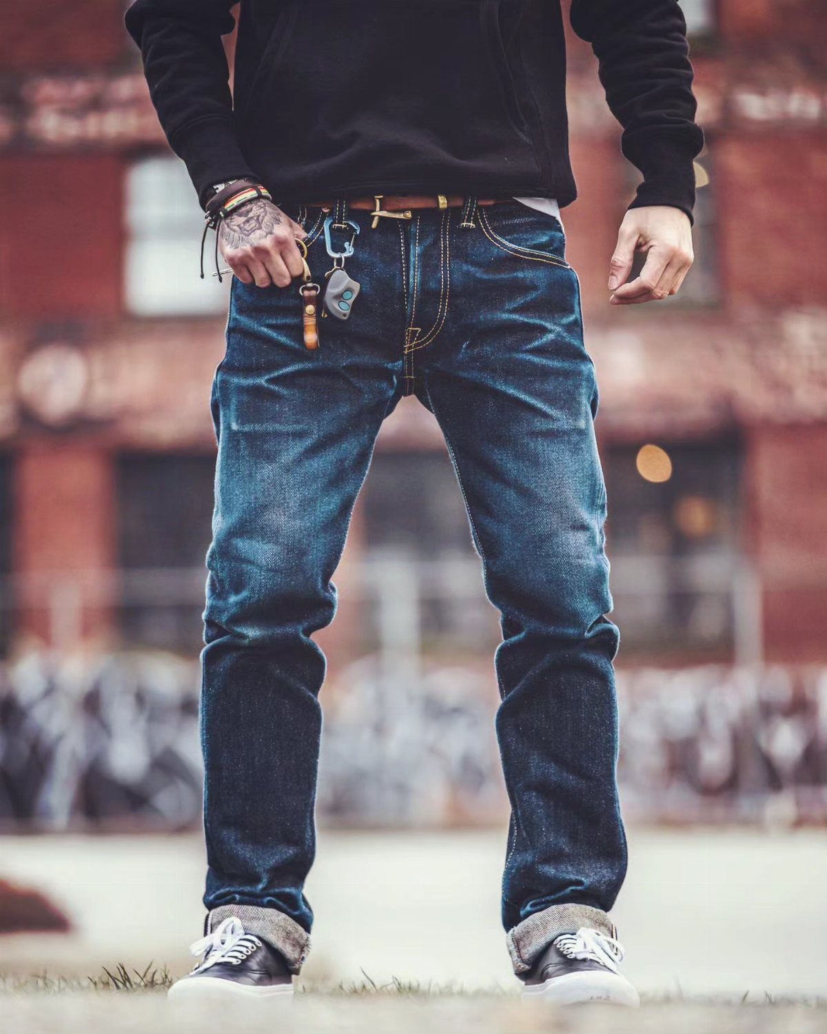 New Men's Fashion Pants: 12 Styles to Refresh Your Wardrobe 8 Man wearing dark blue denim jeans and a black hoodie standing outdoors.