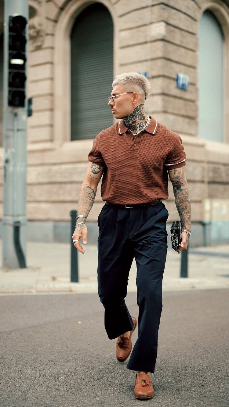 New Men's Fashion Pants: 12 Styles to Refresh Your Wardrobe 9 Man wearing a brown polo shirt and dark navy blue trousers walking outdoors.
