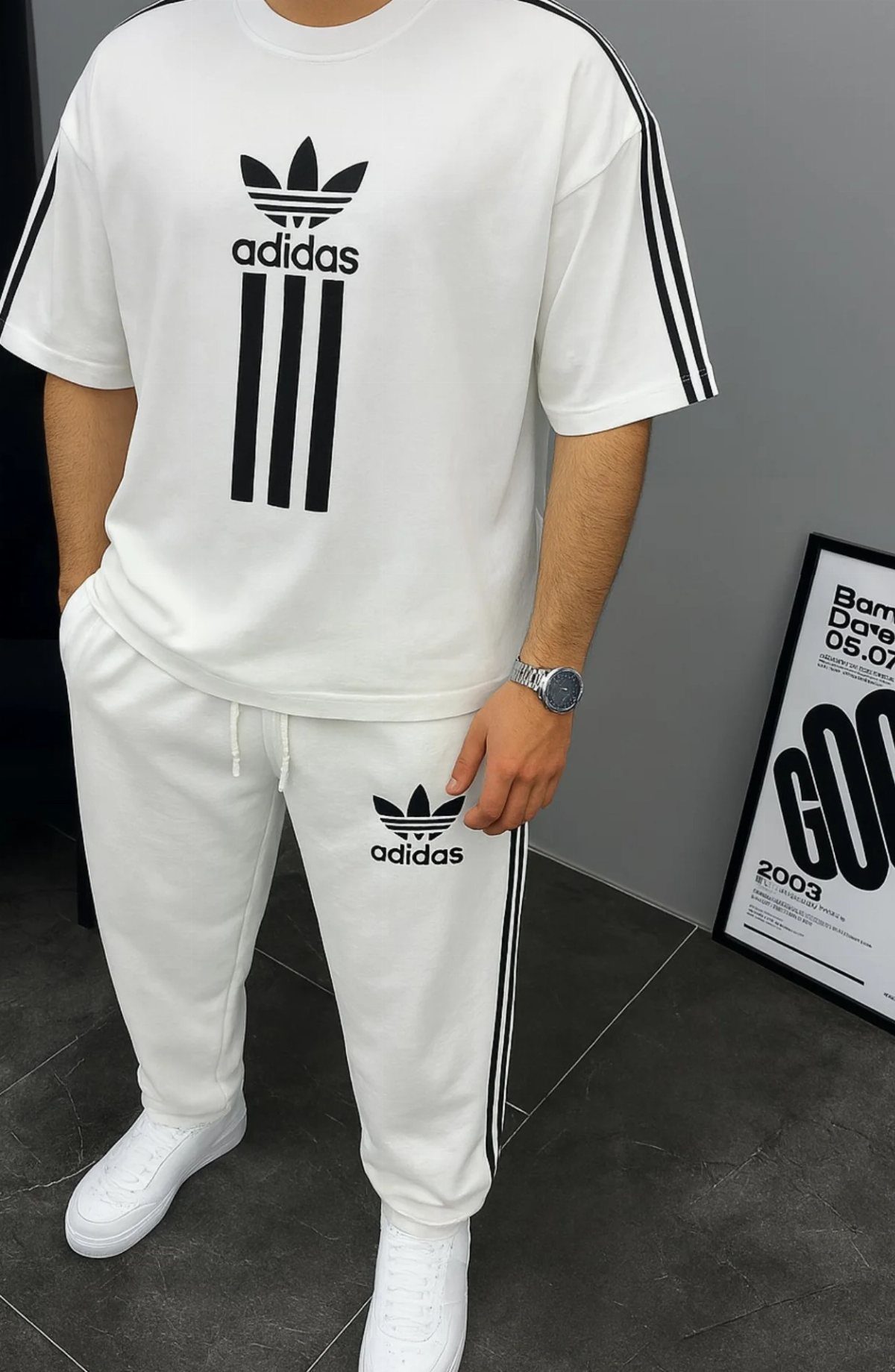 Man wearing a white Adidas t-shirt and matching joggers with white sneakers.