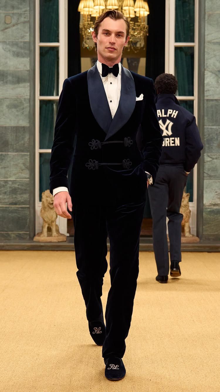 Man wearing a navy velvet tuxedo with a black bow tie on a runway