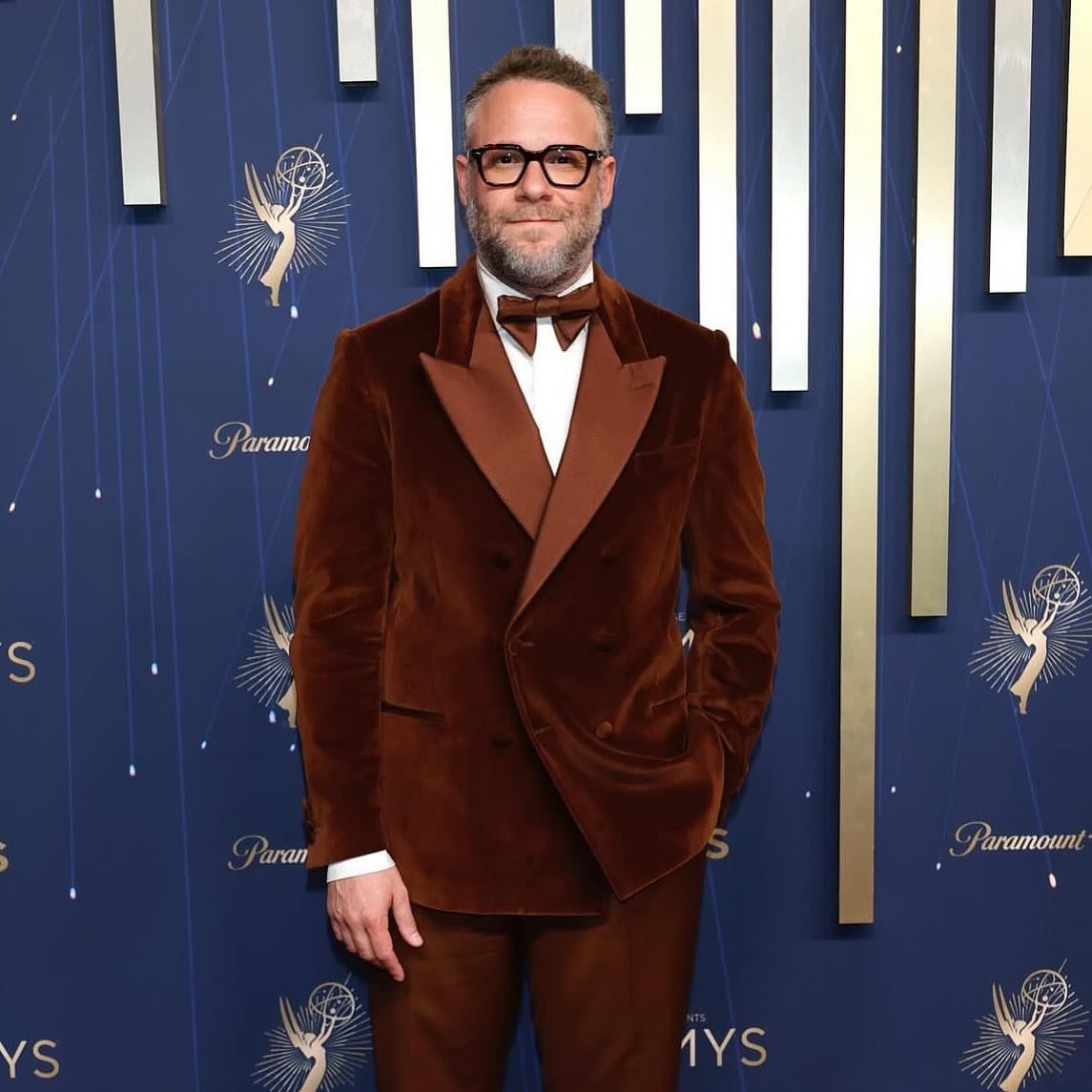Man in brown velvet tuxedo wearing a matching brown bowtie at an awards event.