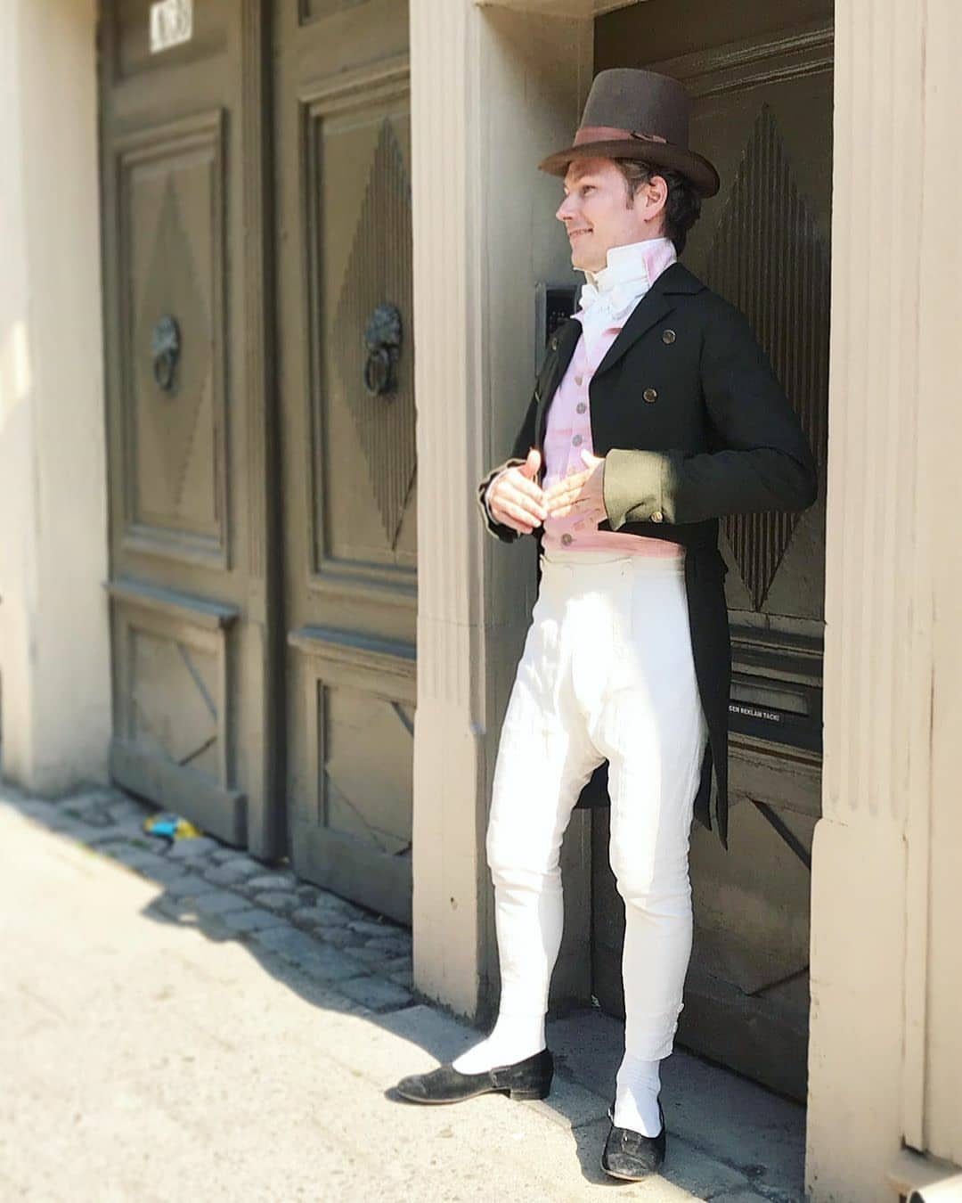 Man in Regency fashion wearing a top hat, tailcoat, and white breeches.
