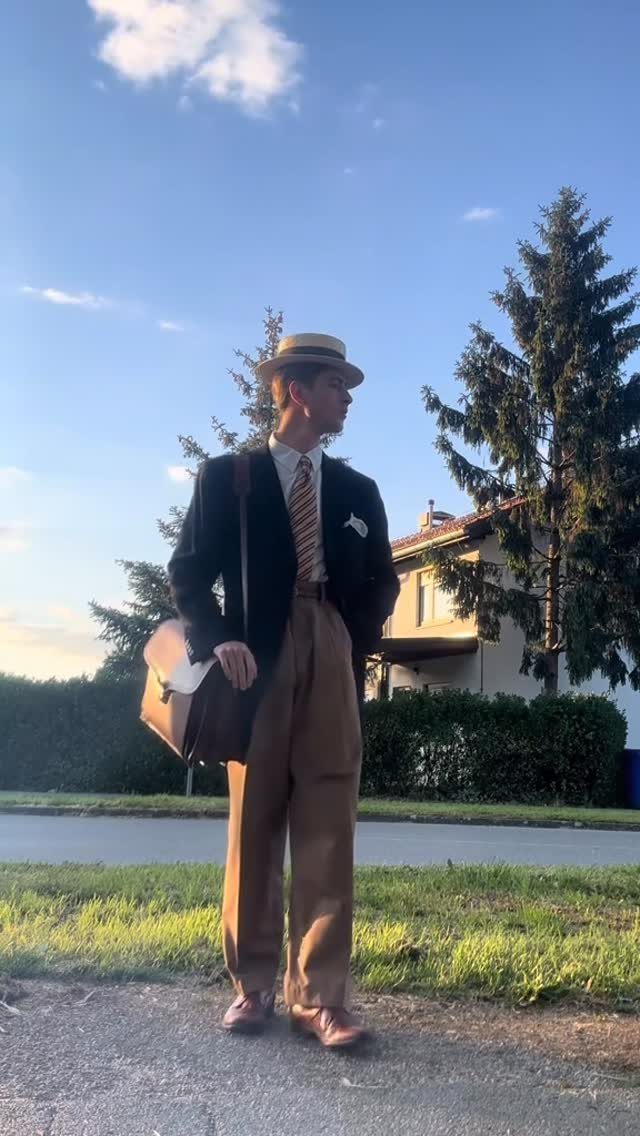 Man in 1920s fashion wearing a boater hat, blazer, and high-waisted tan trousers.