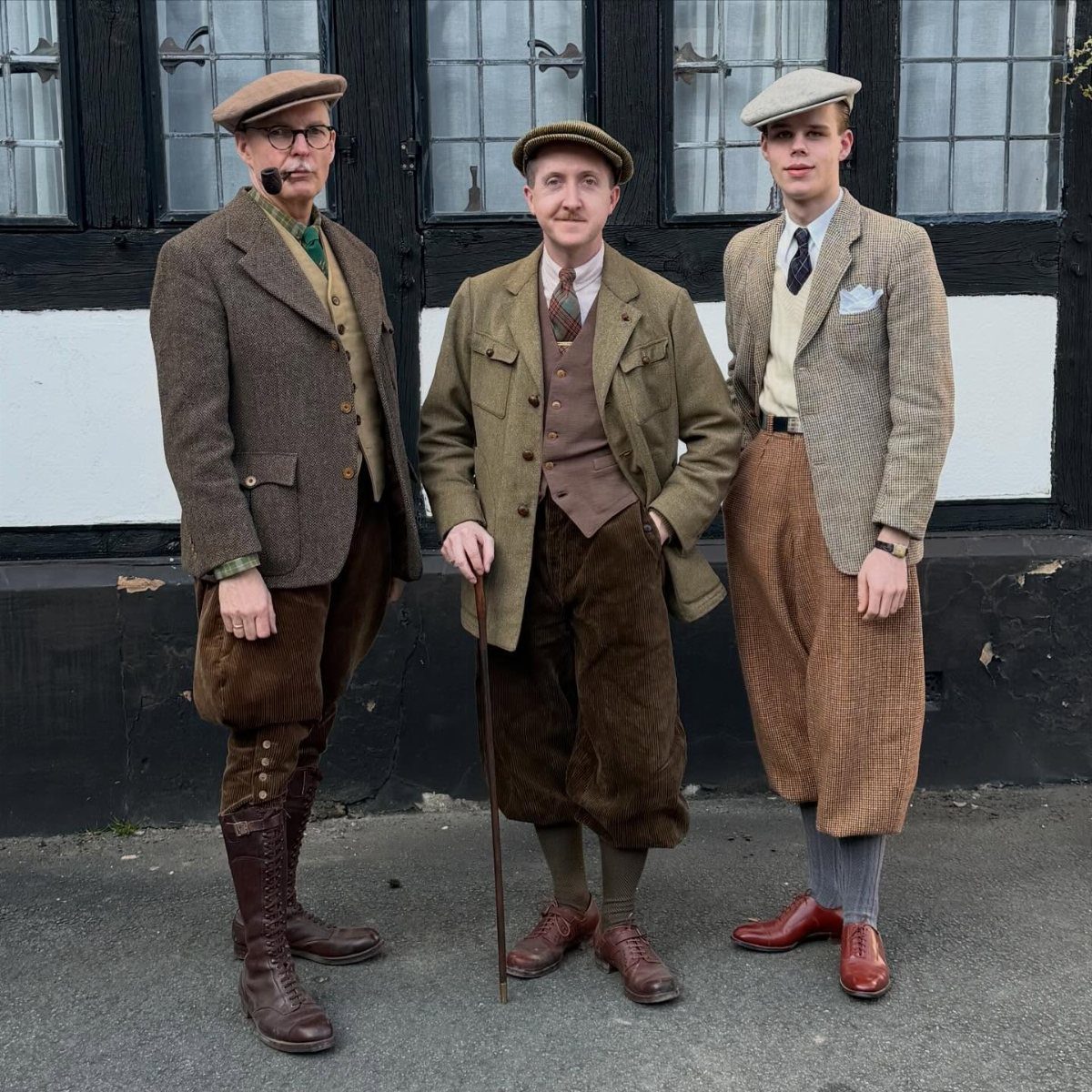 Three men wearing vintage 1920s tweed suits, flat caps, and knickerbockers posing outdoors.
