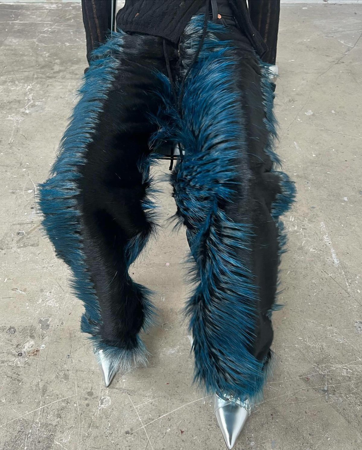 Shaggy teal and black faux-fur pants paired with pointed silver metallic shoes.