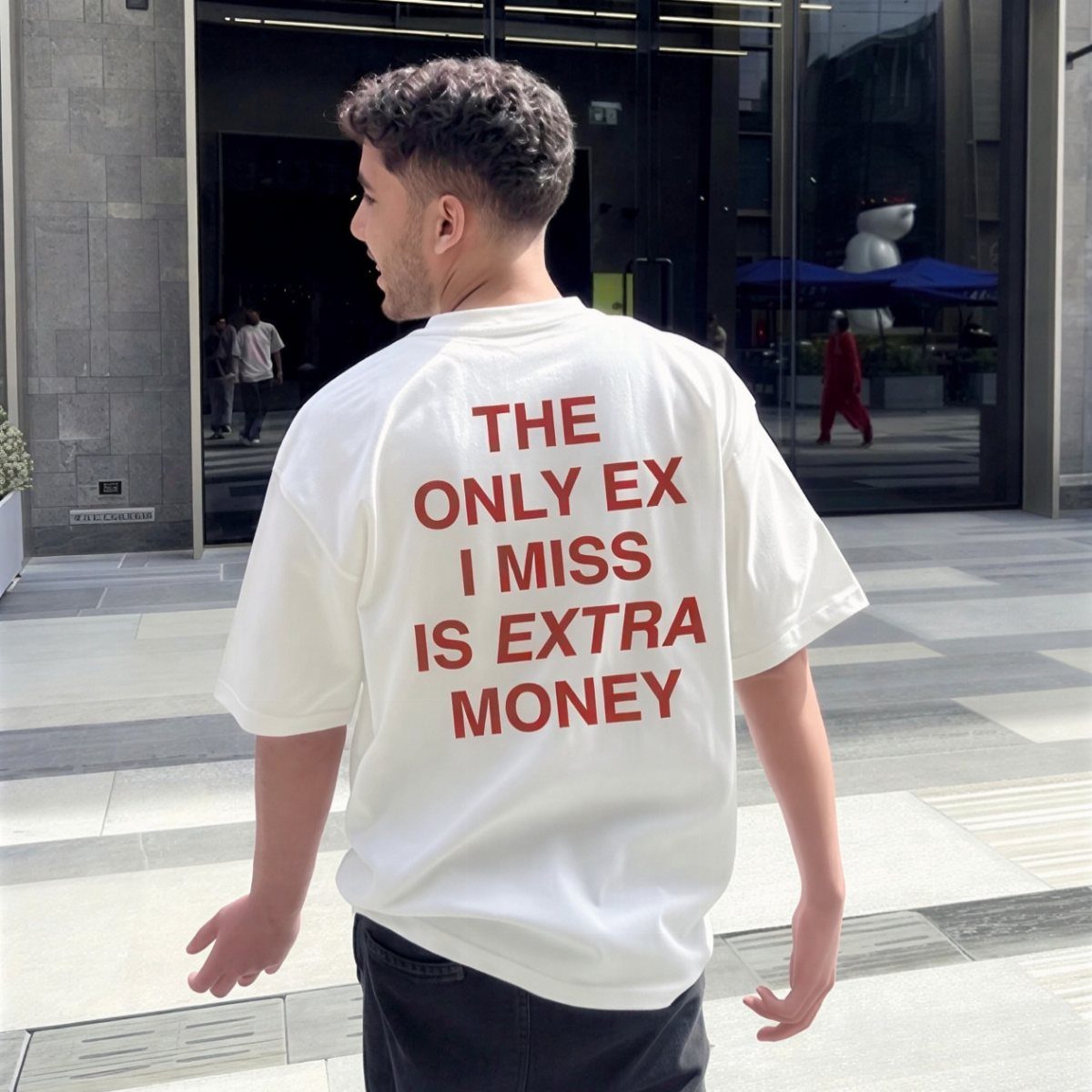 Man wearing a white oversized graphic t-shirt with red text on the back.