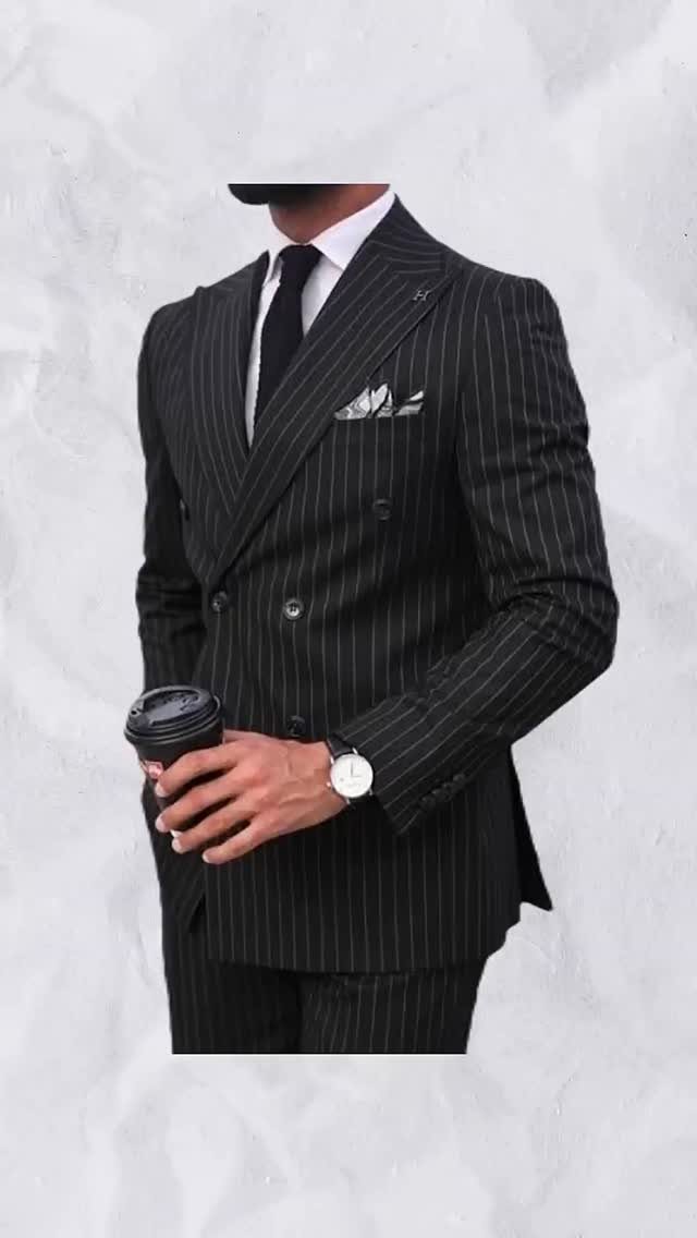 Man in a black pinstripe double-breasted suit holding a coffee cup.
