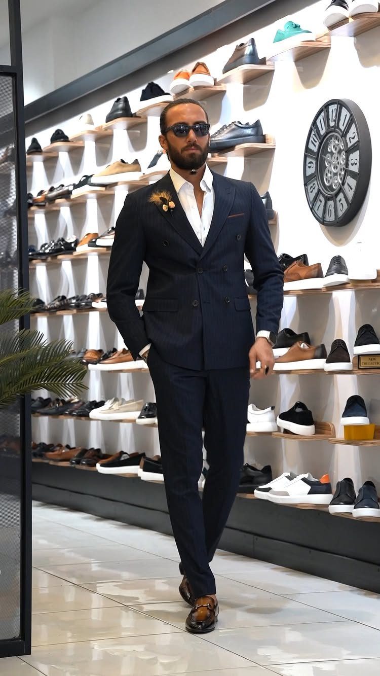 Man in a navy blue tailored suit and white shirt standing in a shoe store.