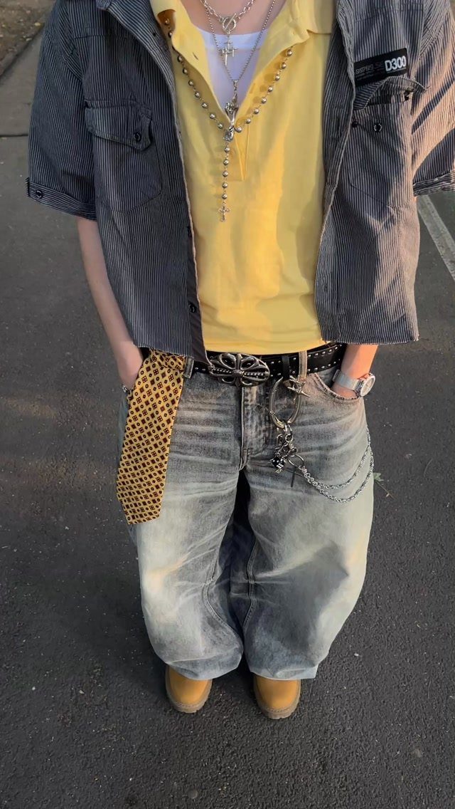 Baggy light-wash denim jeans paired with a yellow polo and grey shirt.